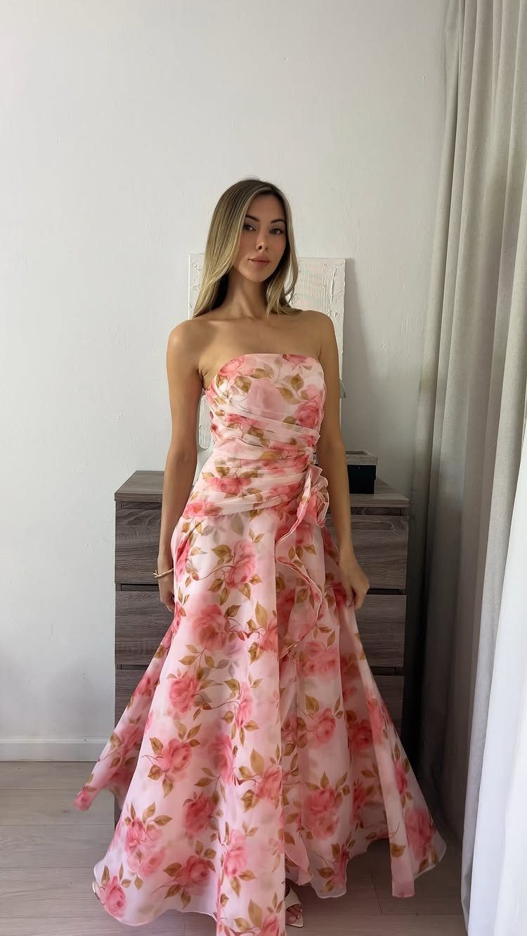 A woman posing in a strapless pink floral A-line gown indoors.