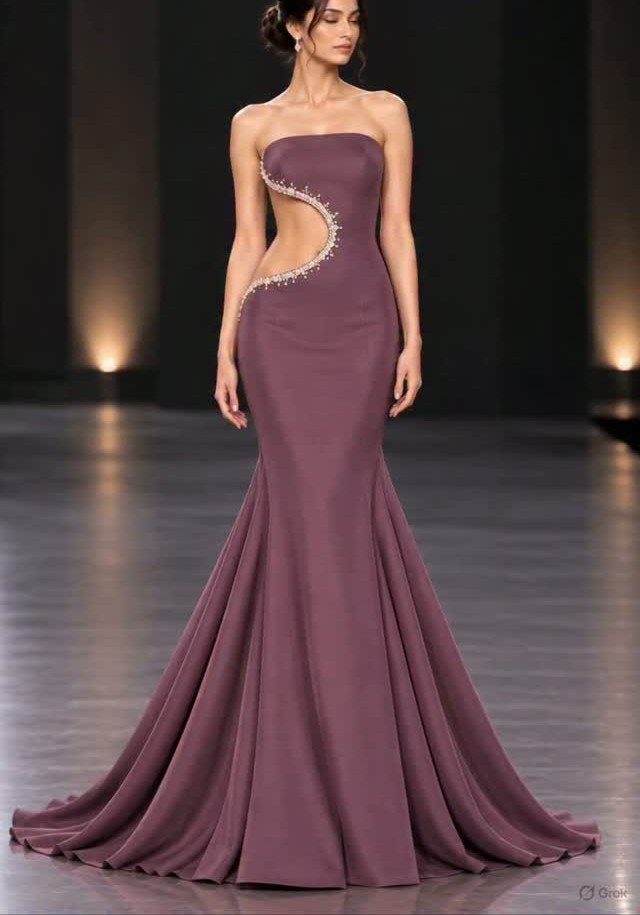 Woman in a mauve mermaid gown with a decorative waist cutout standing on a dark runway.