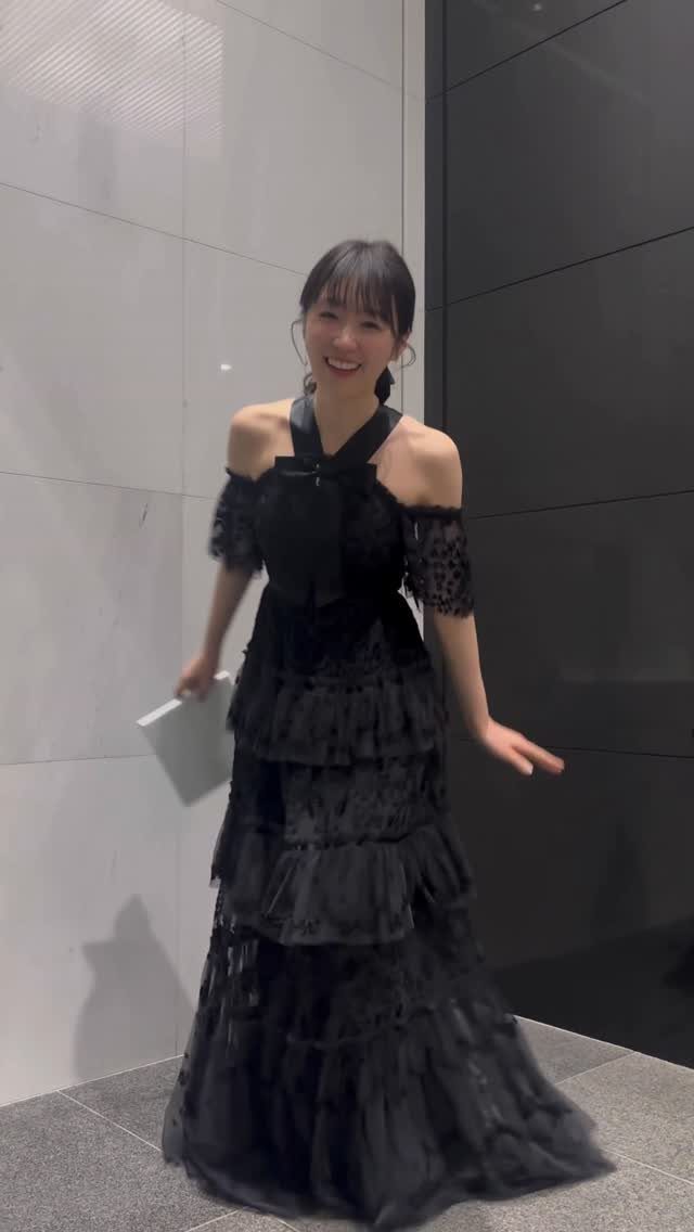 A woman smiling in a black tiered halter gown with ruffled layers.