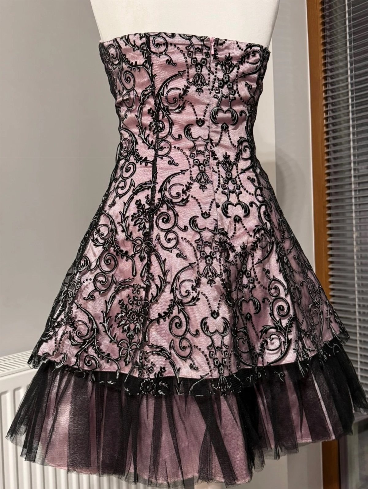 A pink strapless mini dress with black lace embroidery and a black tulle ruffle hem.