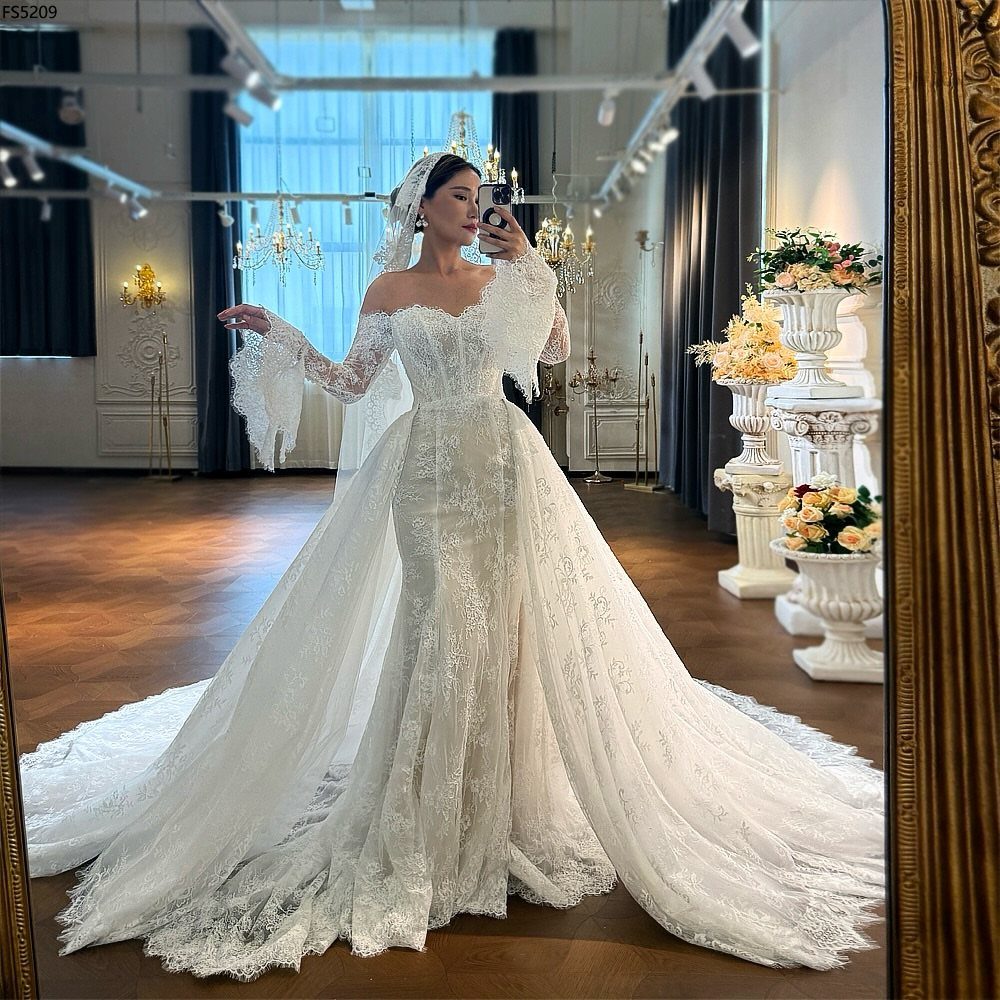 Woman in a lace mermaid wedding dress with a corset bodice posing in a mirror.