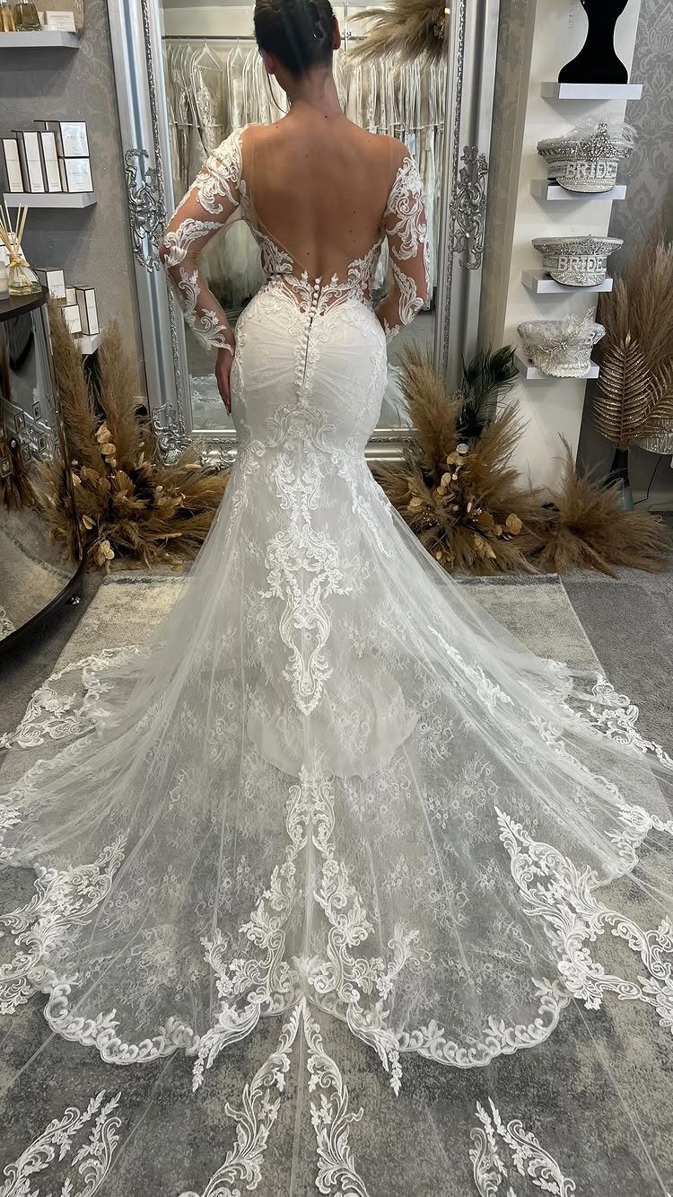 Woman in a white lace mermaid wedding dress with a long, detailed train.
