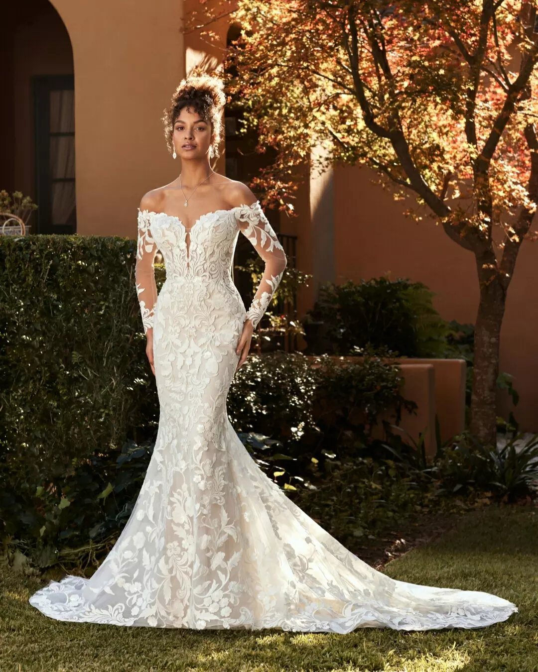 Woman wearing a white lace off-the-shoulder wedding dress that flares at the bottom.