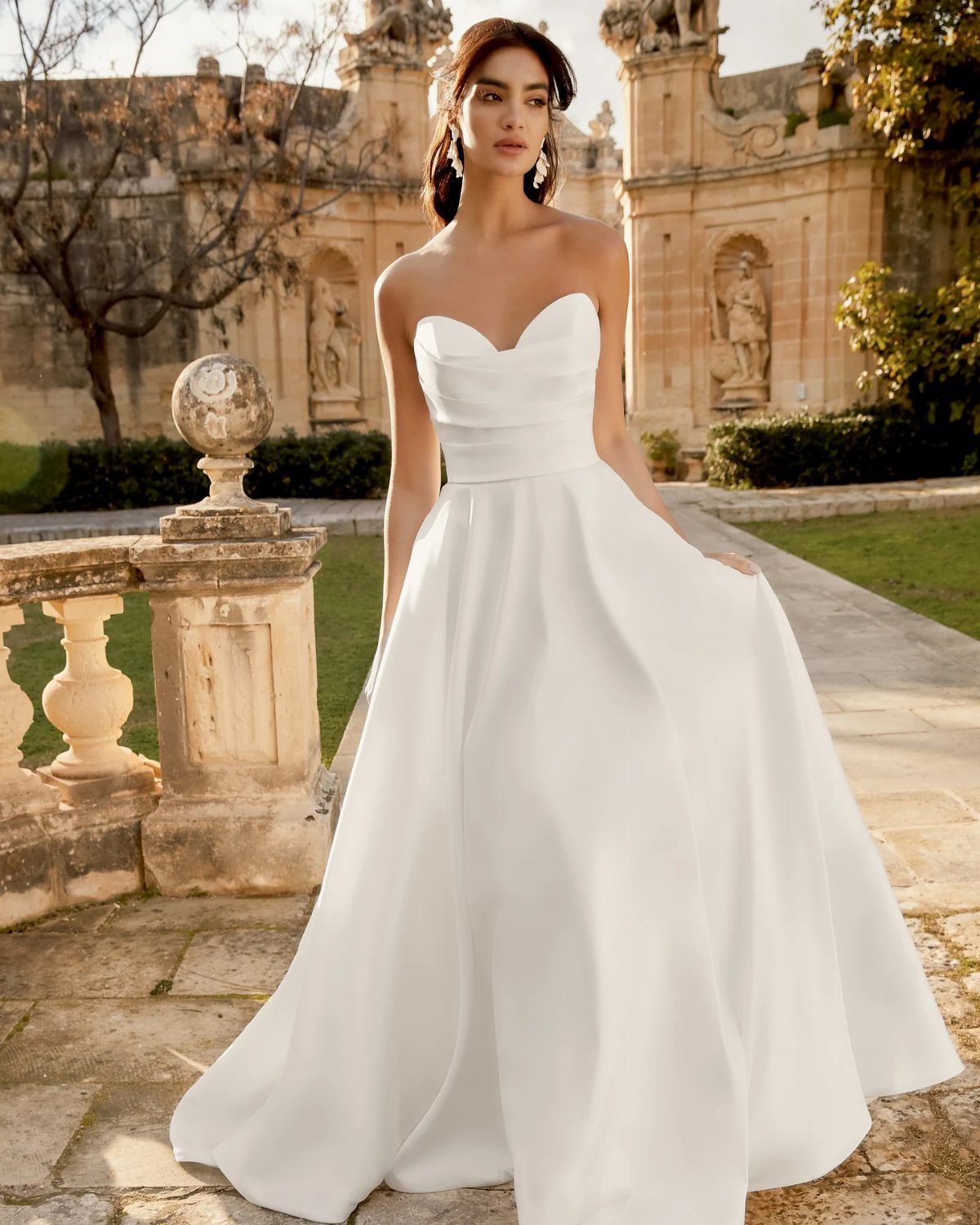Woman wearing a white strapless A-line wedding dress standing on a stone terrace.