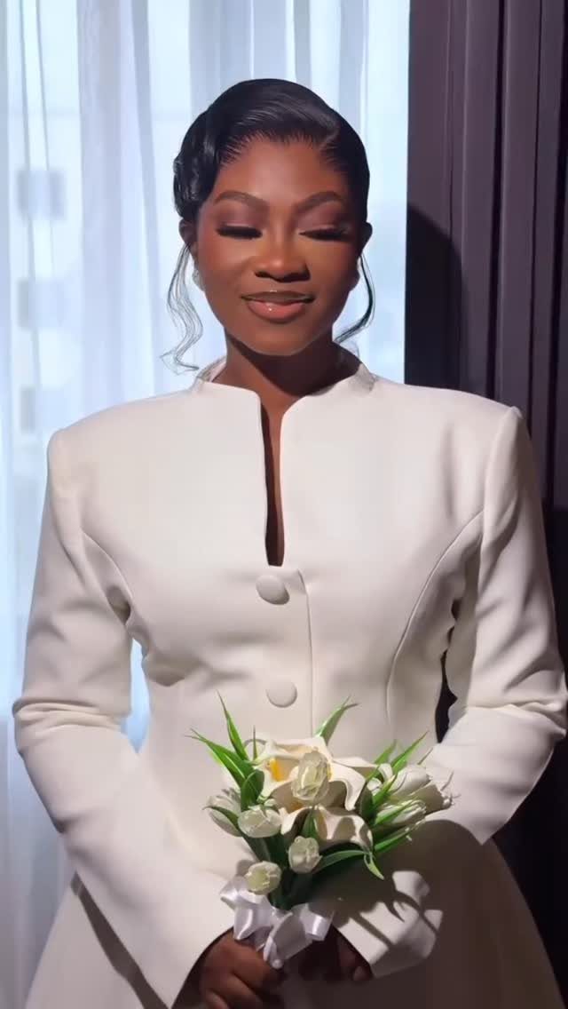 Woman in a minimalist white structured wedding dress holding a calla lily bouquet.