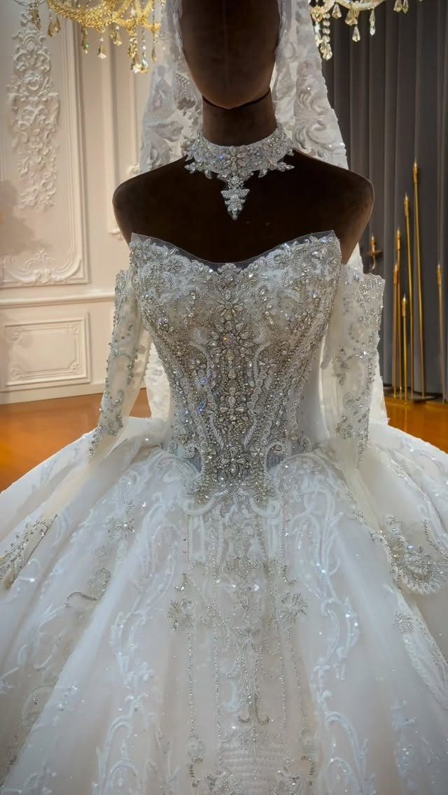 Ornate white wedding gown with heavy silver beadwork and crystals displayed on a mannequin.