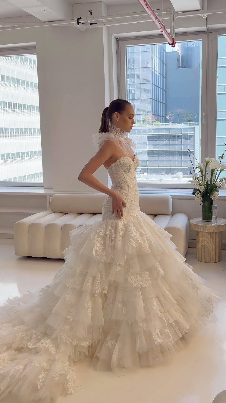 Woman wearing a white mermaid wedding dress with a voluminous tiered tulle skirt.