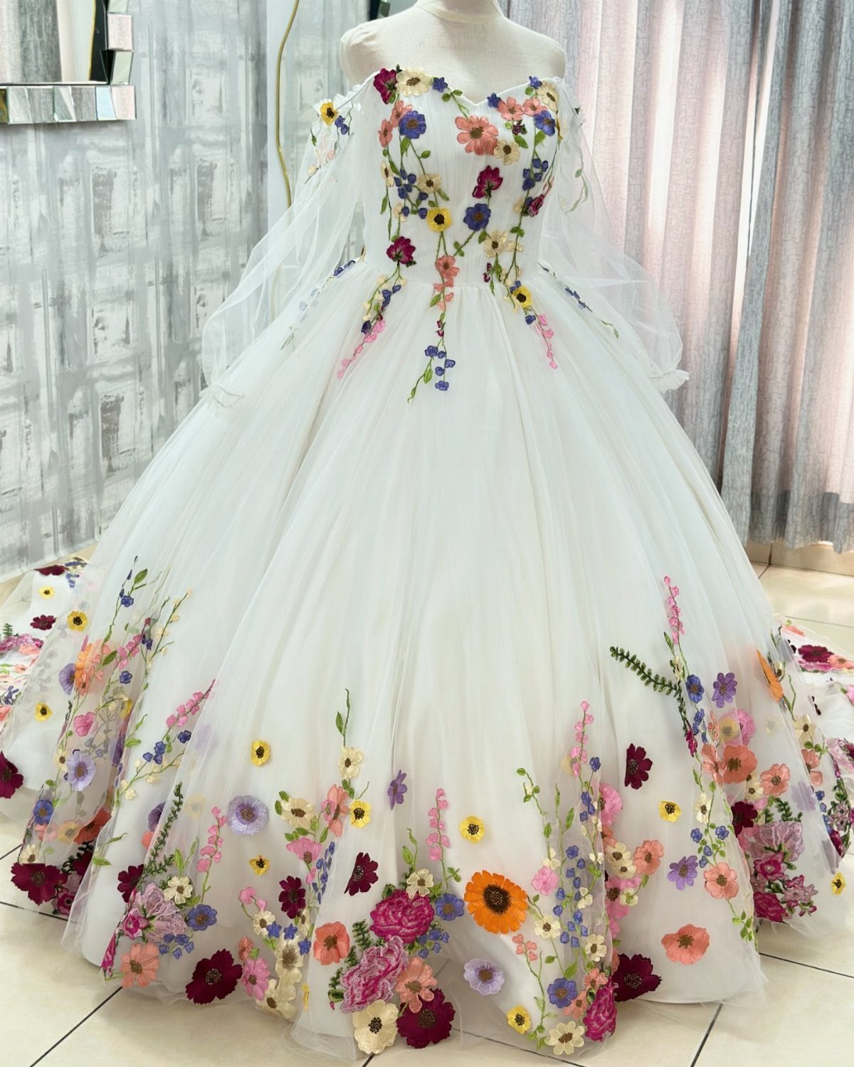 White ball gown wedding dress with colorful floral embroidery on a mannequin.