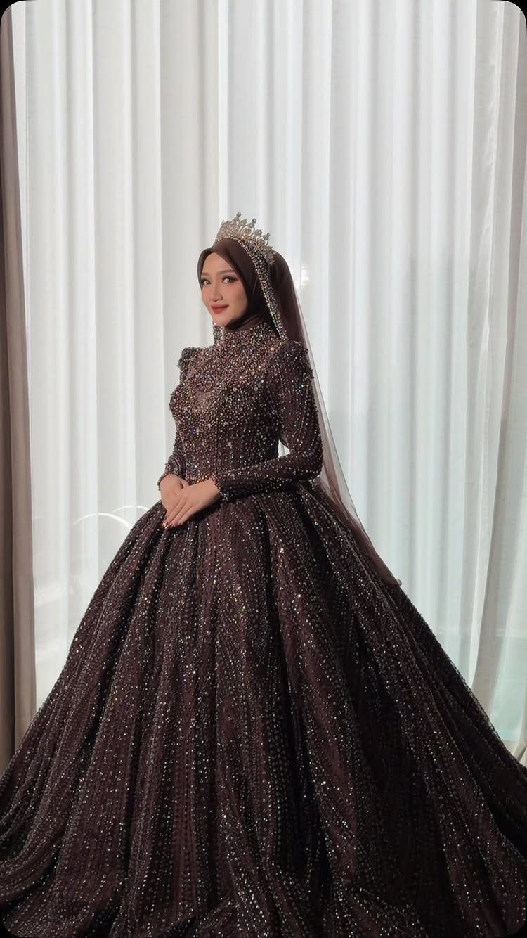 A woman in a shimmering dark ball gown wedding dress wearing a crown and veil.