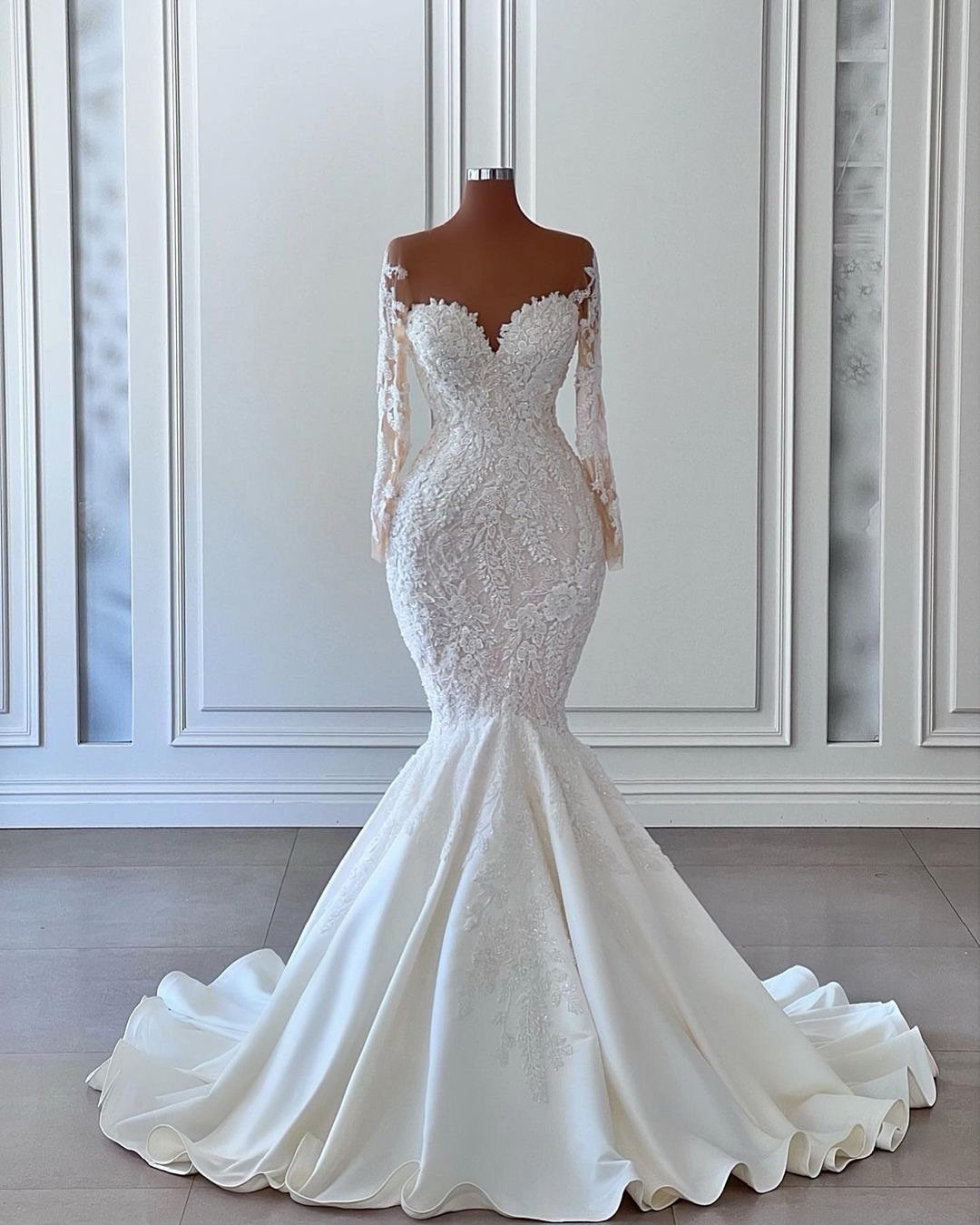 Lace mermaid wedding dress with off-the-shoulder sleeves displayed on a mannequin.