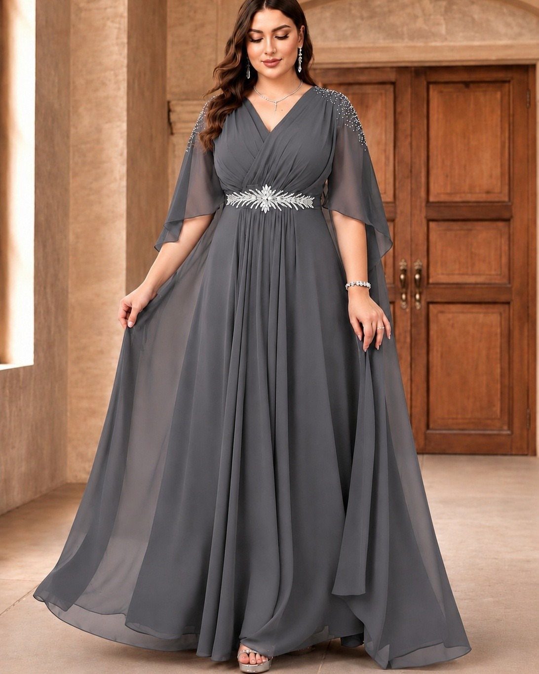 Woman posing in a flowing charcoal grey chiffon wedding guest dress with silver embellishments.