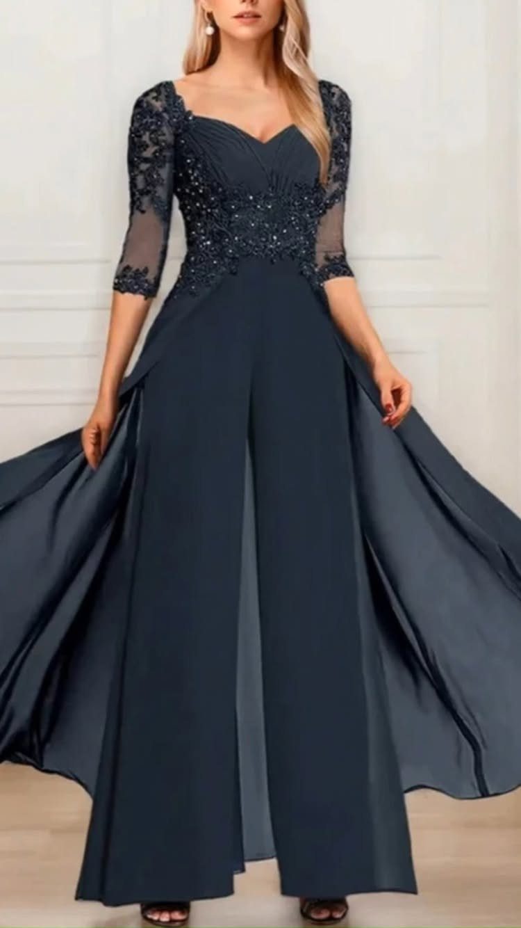 Woman posing in a navy blue lace jumpsuit with a long, flowing chiffon skirt.
