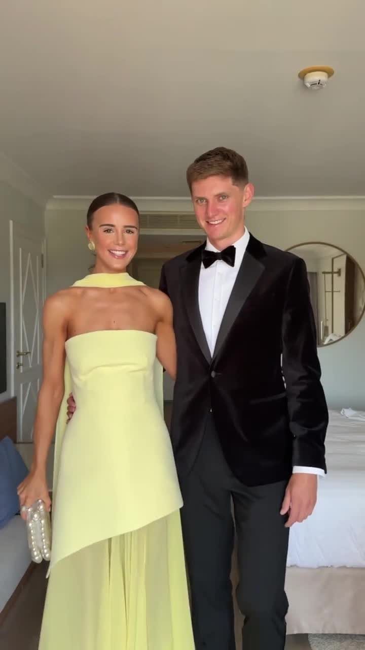 A man in a black velvet tuxedo and a woman in a pale yellow gown posing together.