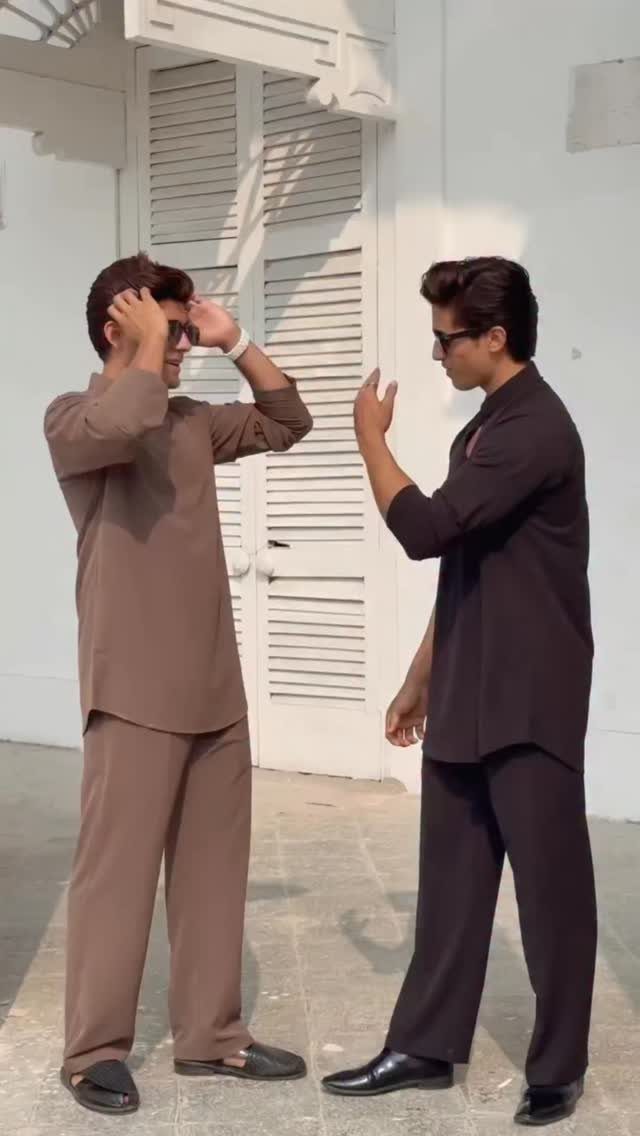 Two men posing in coordinated tan and black tunic and trouser sets.
