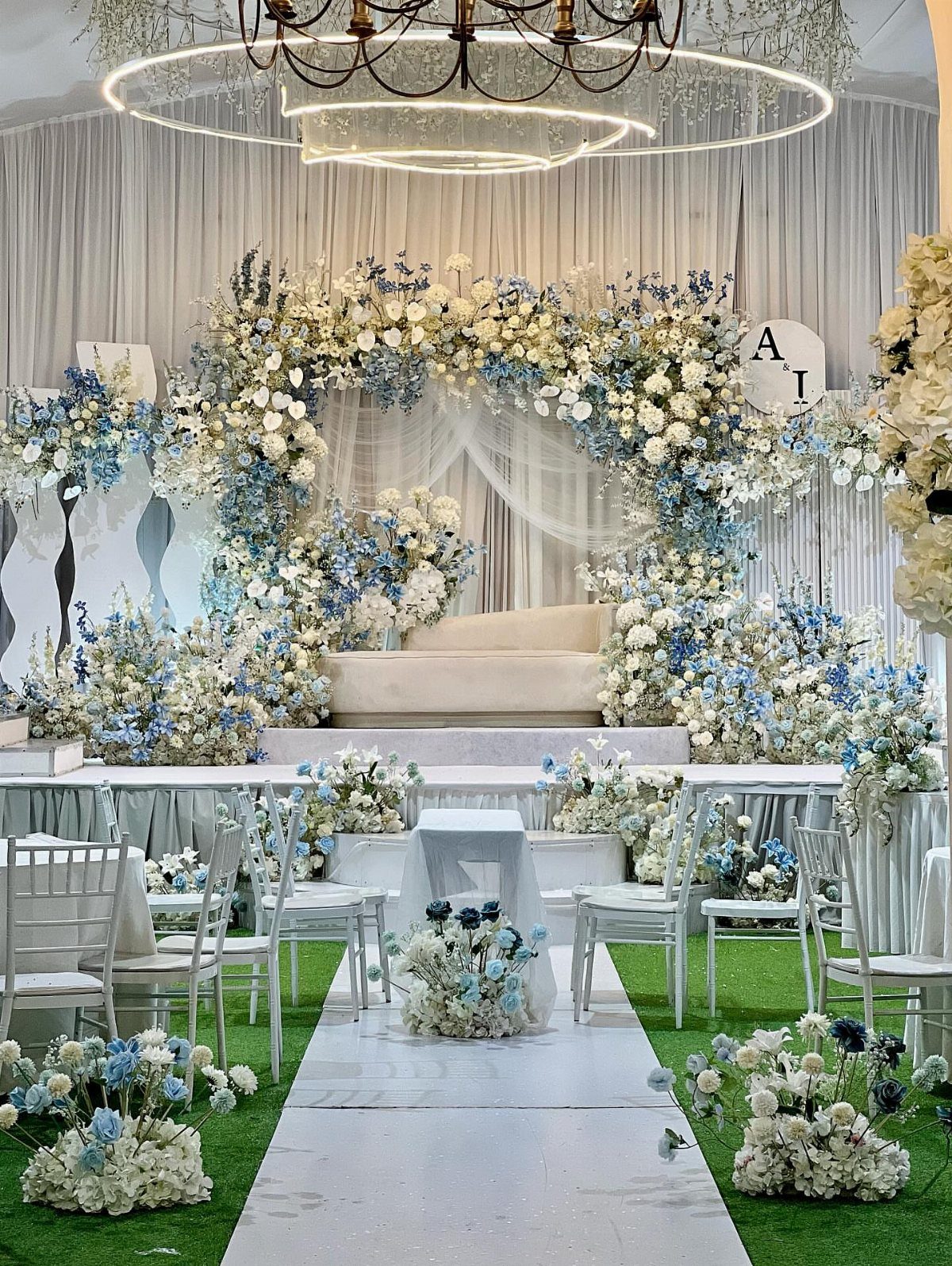 Dusty blue and white floral arrangements decorate a wedding ceremony aisle and archway.