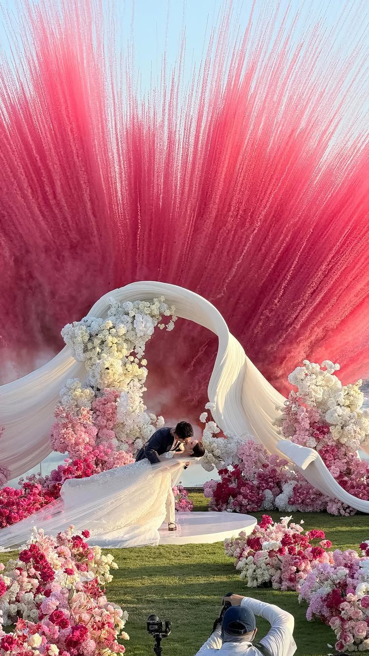 Pink and white floral wedding decor with a dramatic pink backdrop and white fabric arch.