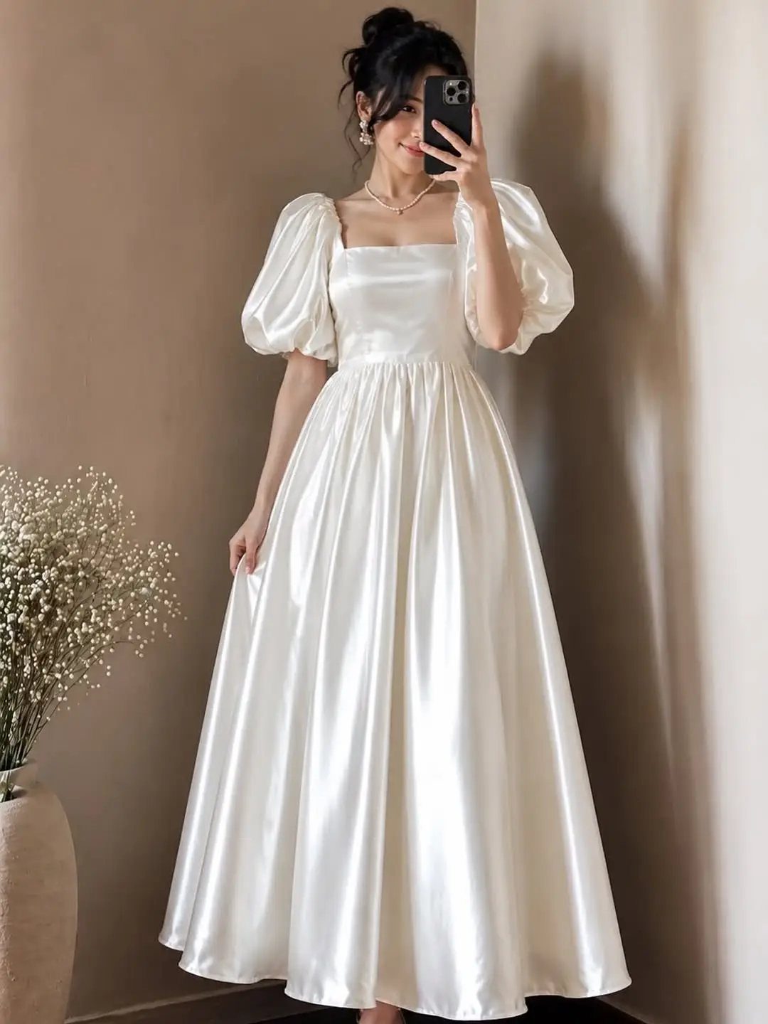 Woman in a white satin puff-sleeve dress posing for a mirror selfie.
